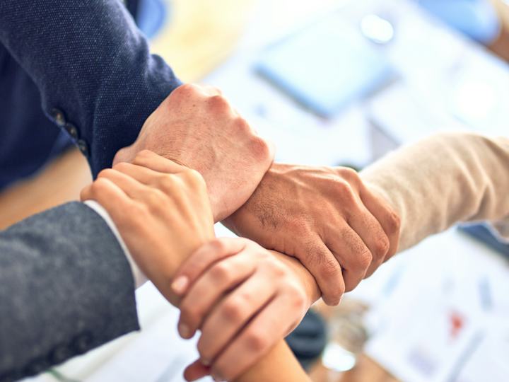 Quatre personnes croisent leurs mains en signe d'engagement commun